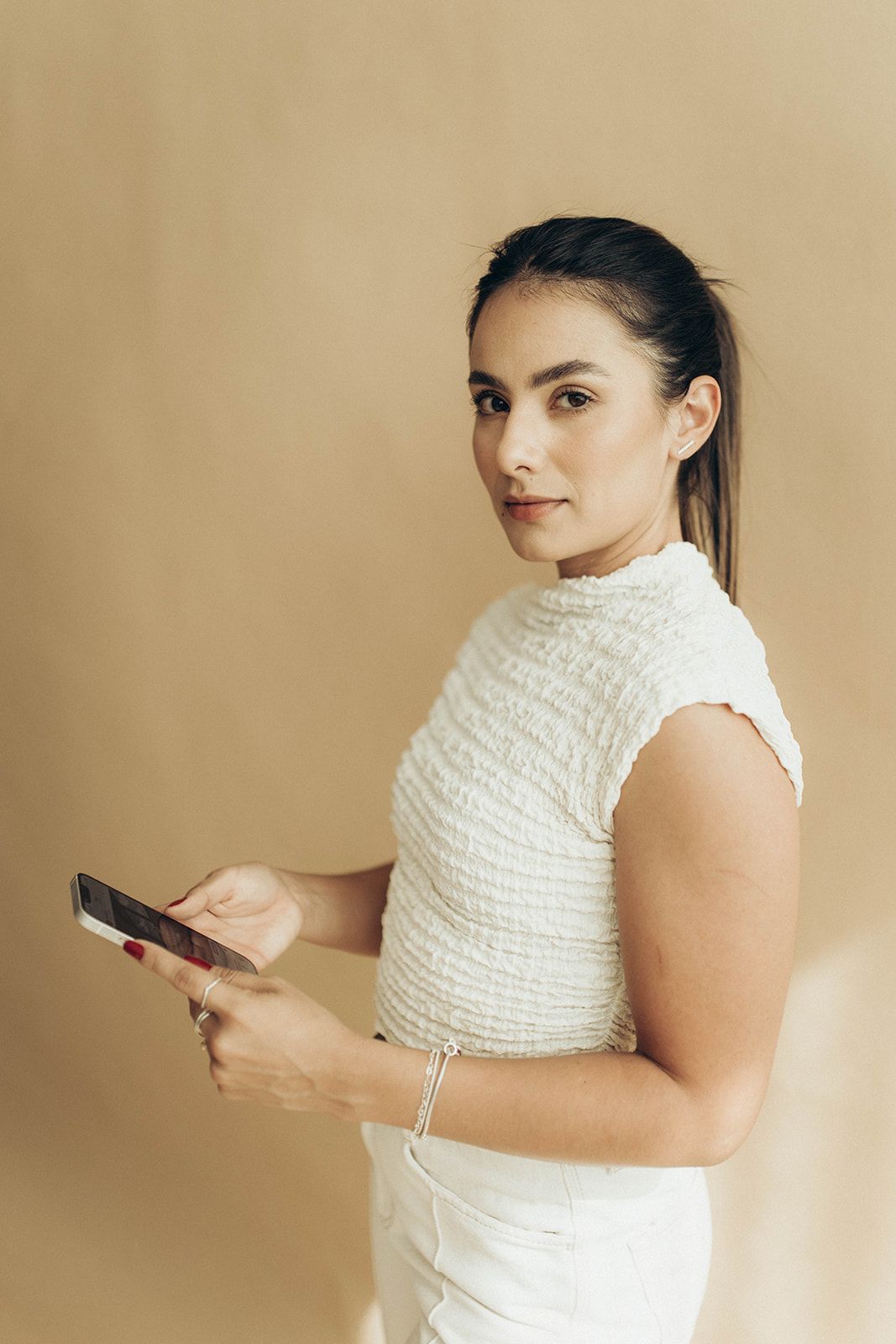 Leticia Gabriela Inacio com um celular nas mãos, olhando para a câmera.